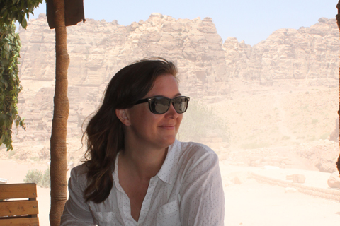 A young woman in sunglasses looking out at a desert landscape 